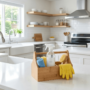A bright modern white kitchen with a wooden cleaning caddy, spray bottle, and yellow rubber gloves on a white countertop.